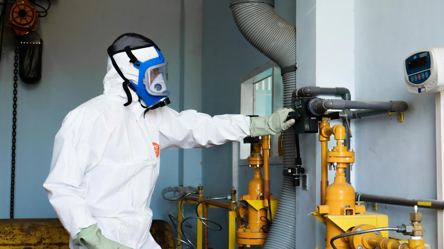Pracownik w odzieży ochronnej kontroluje instalację przemysłową pod kątem bezpie