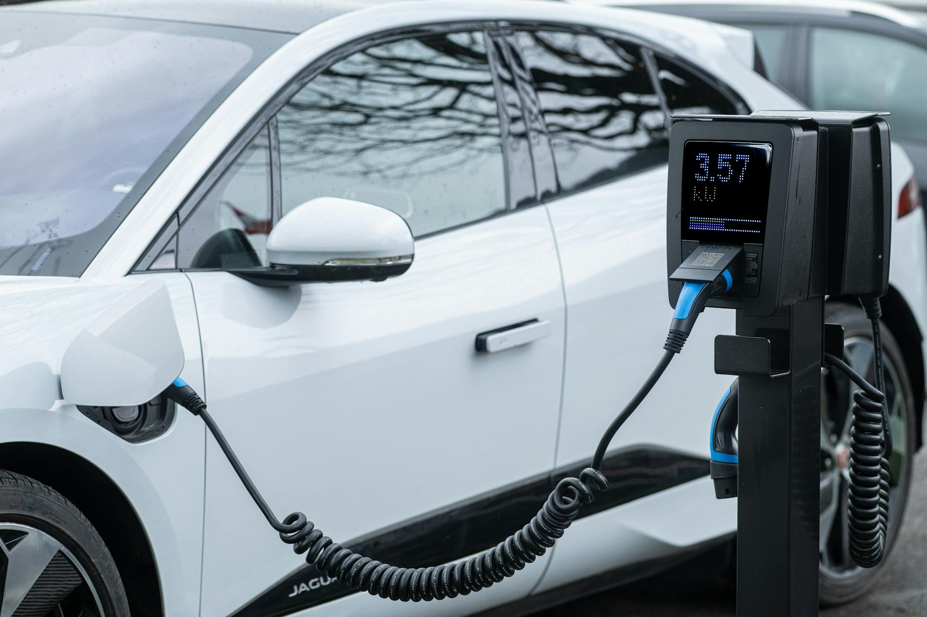 Zbliżenie na ładowany samochód elektryczny podłączony do stacji