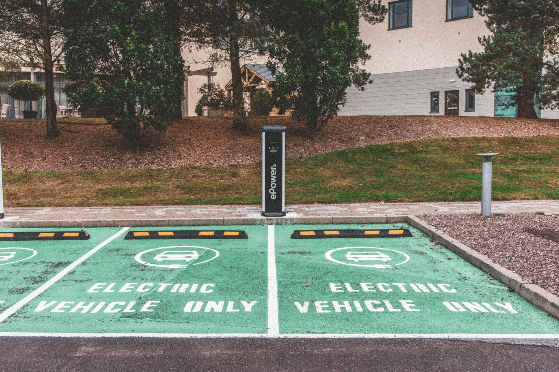 Samochody elektryczne czy hybrydy plug-in – co dziś bardziej opłaca się kierowcom w Polsce Zielony samochód elektryczny podłączony do ładowarki w mieście