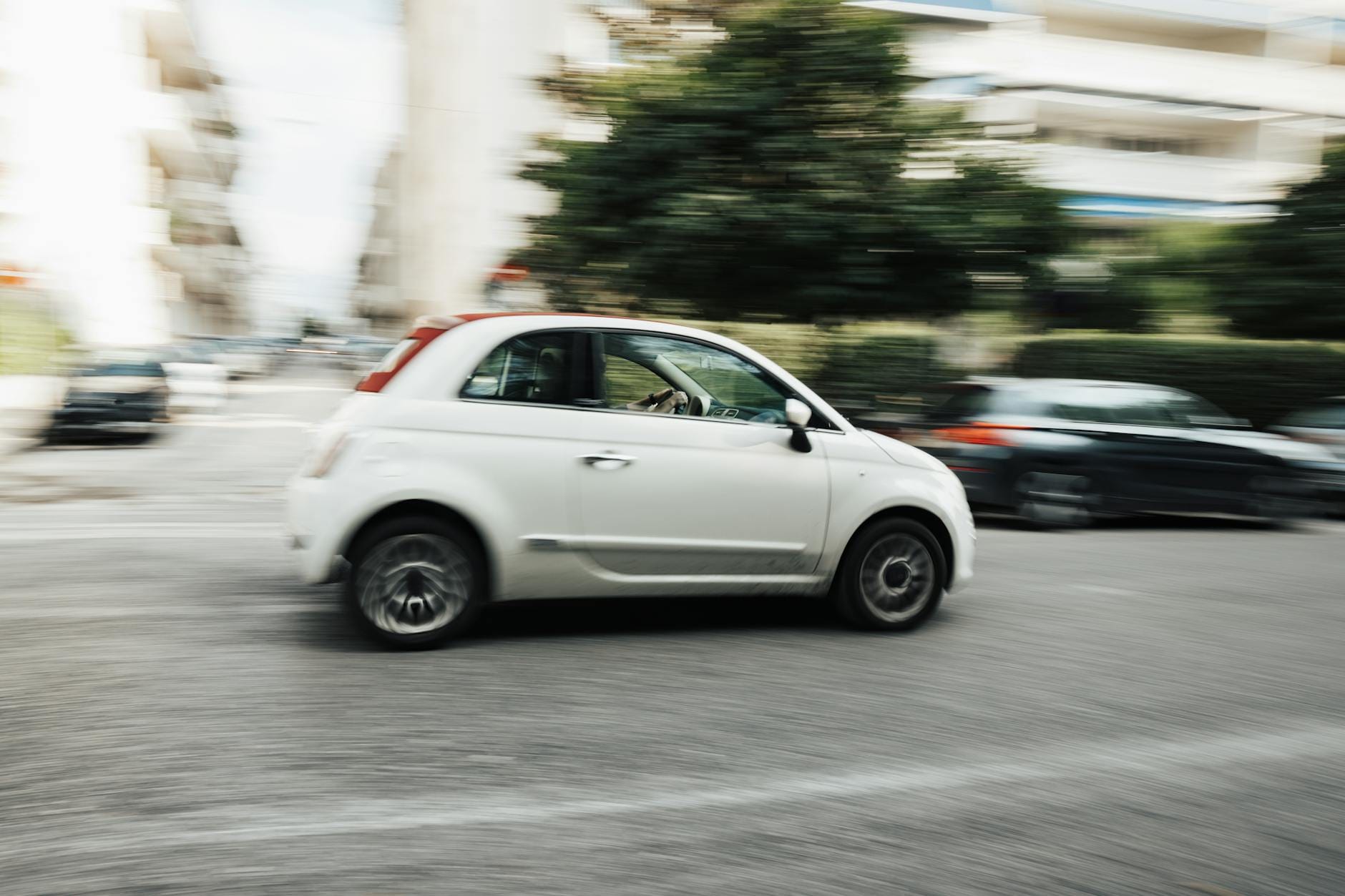 Fiat Panda jako auto miejskie: spalanie, typowe usterki i koszty serwisu po latach Biały samochód jedzie szybko ulicą w centrum miasta