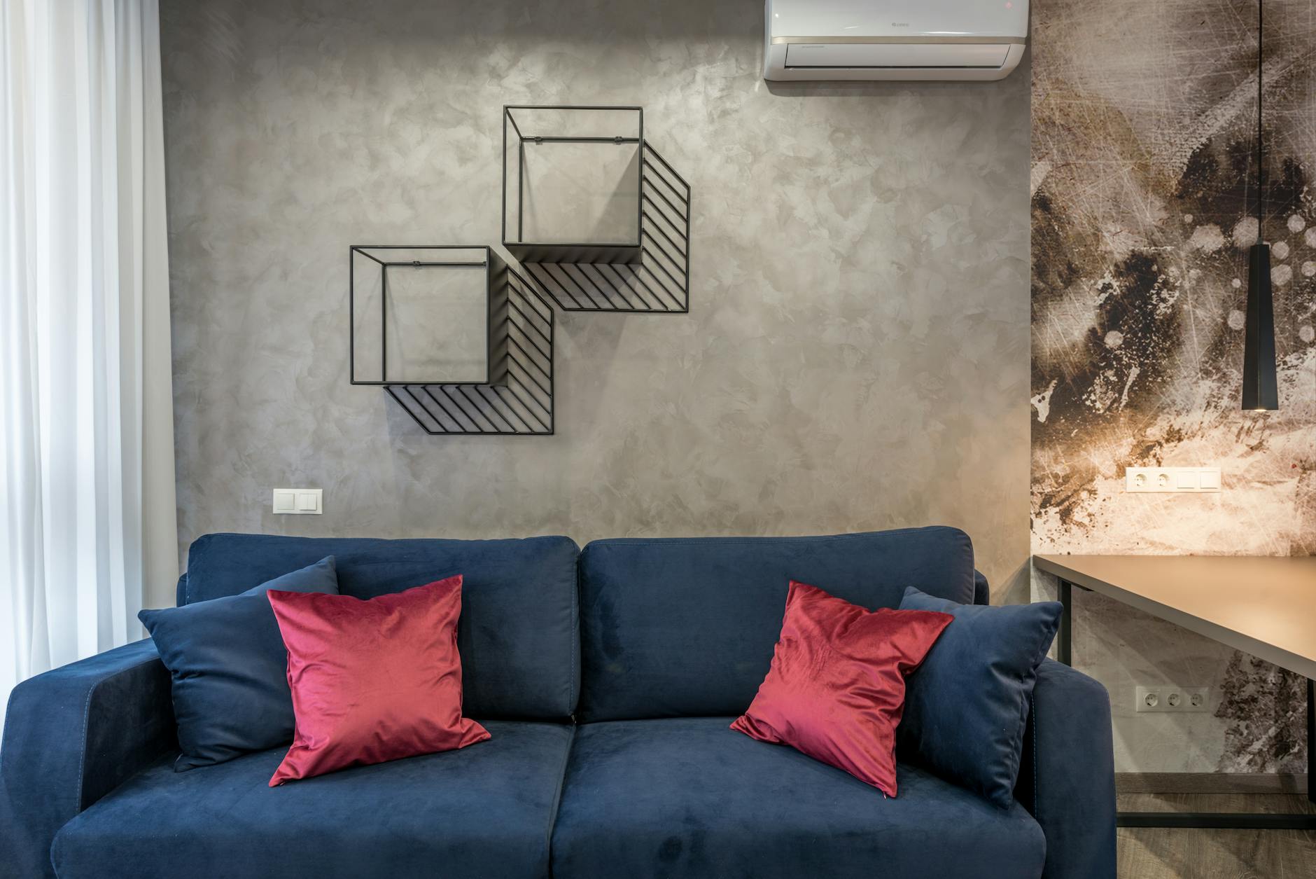 Nowoczesny salon z beżową sofą i geometrycznymi półkami na ścianie