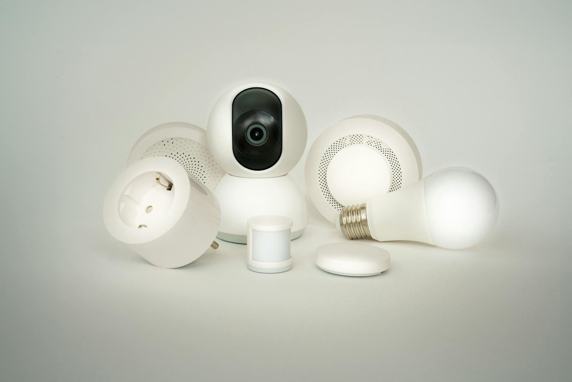 Zestaw urządzeń smart home IoT: żarówki, gniazdka i kamery na białym tle