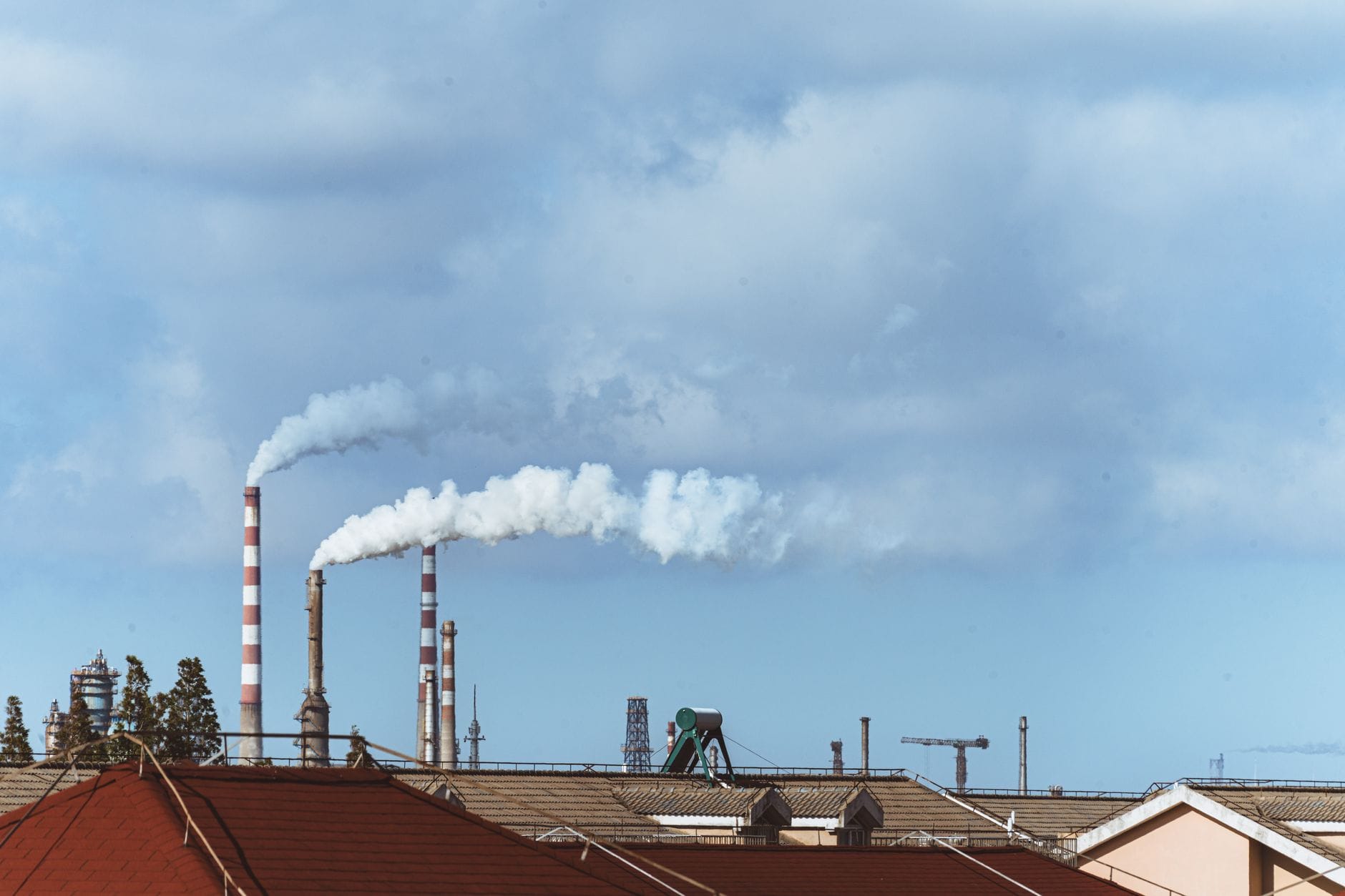 Najczęstsze naruszenia norm jakości powietrza w halach produkcyjnych i ich konsekwencje Kominy fabryczne emitujące dym nad miastem jako przykład zanieczyszczeń
